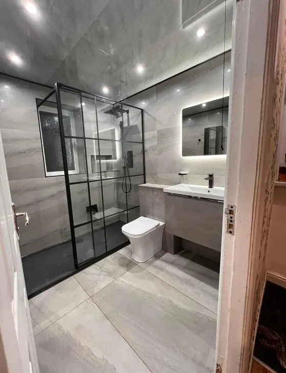 Bathroom with a black framed shower screen, wall hung vanity and backlit mirror