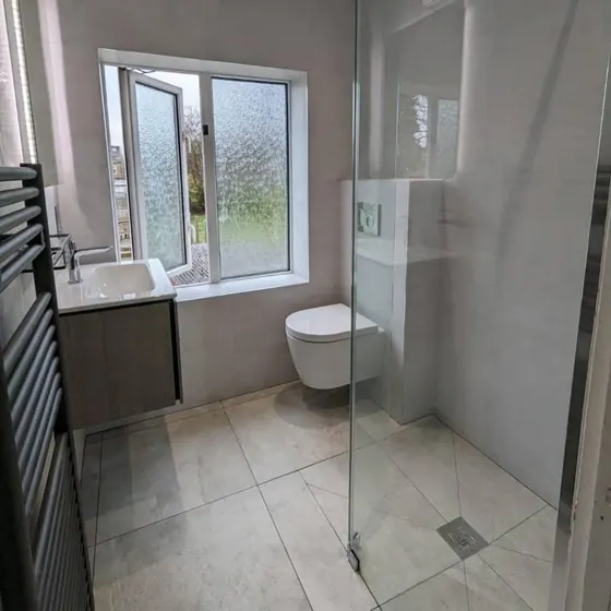 Level access wet room with a linear floor drain and glass screen